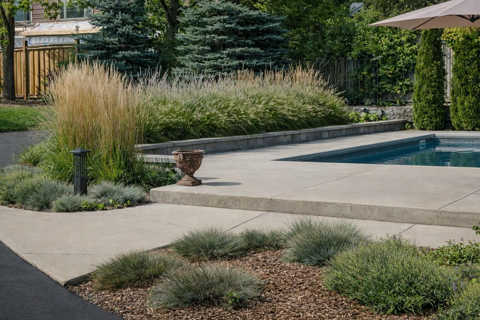 Backyard natural swimming pond with wooden deck, lounge chairs, umbrellas, and landscaped garden creating a relaxing outdoor living space.