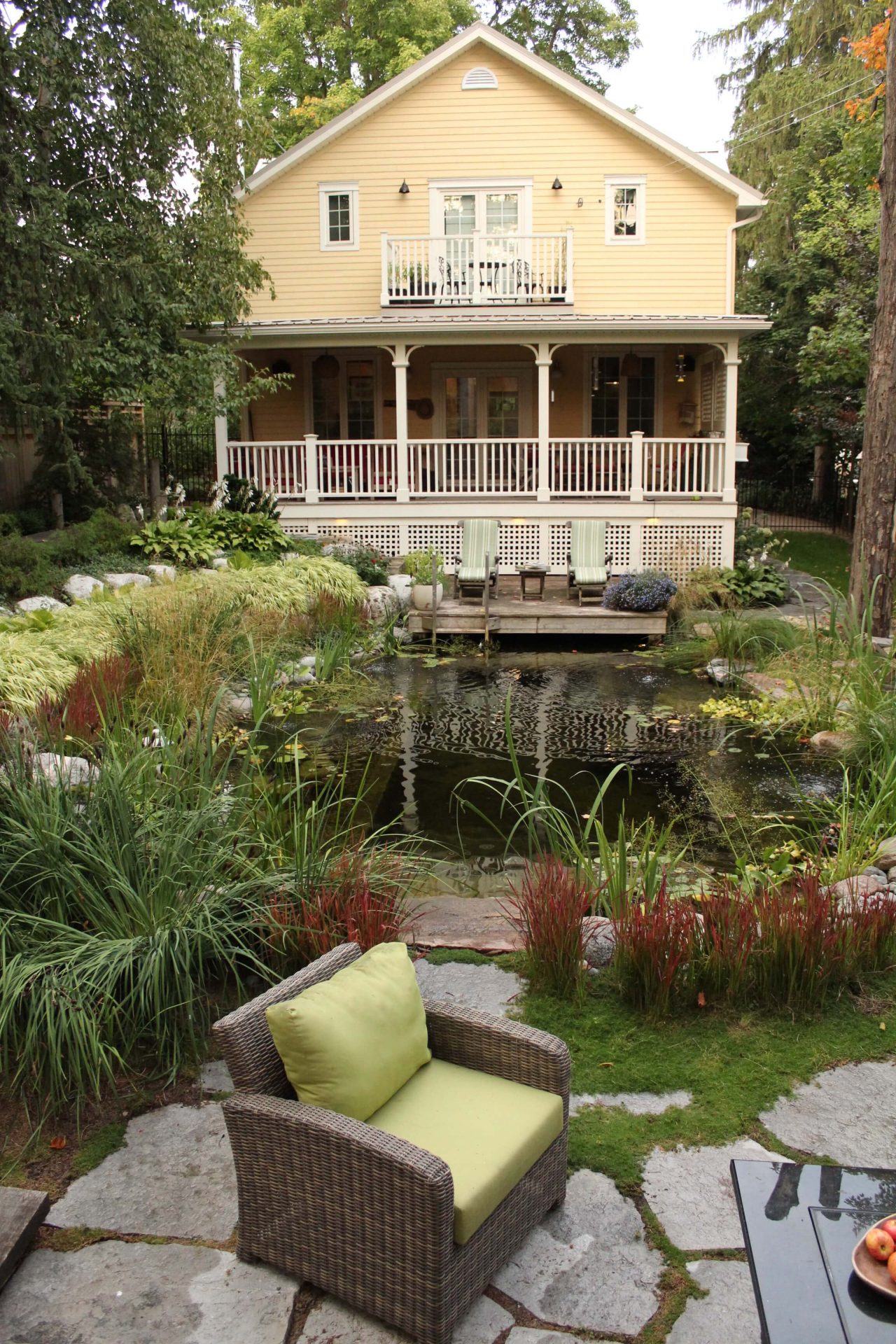 View from the patio at The Junction in Guelph overlooking the natural swim pond, layered planting, and the rear of the home.
