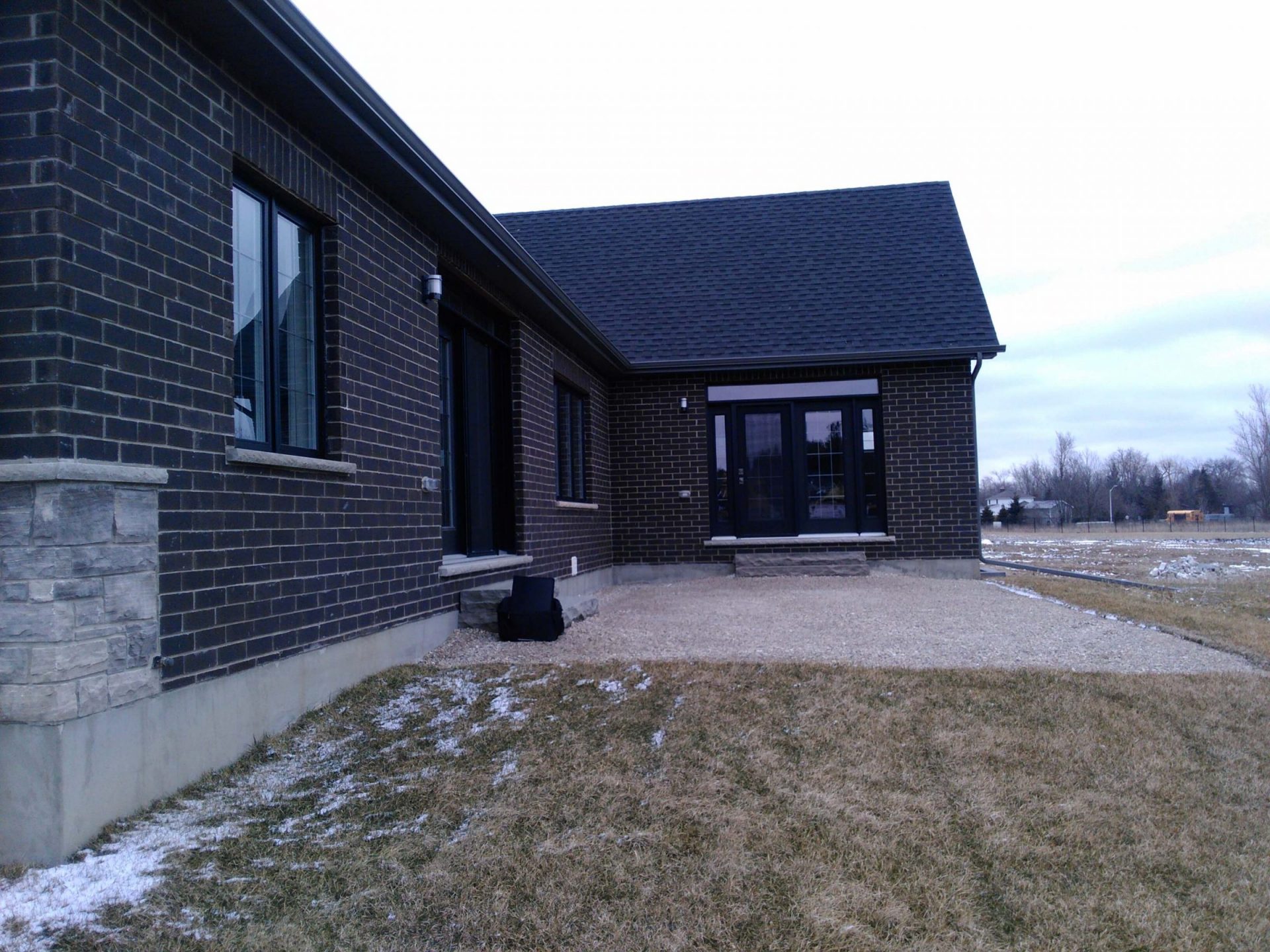 Angled view of the rear entry with a bare yard and unfinished outdoor space before the deck and landscaping were built