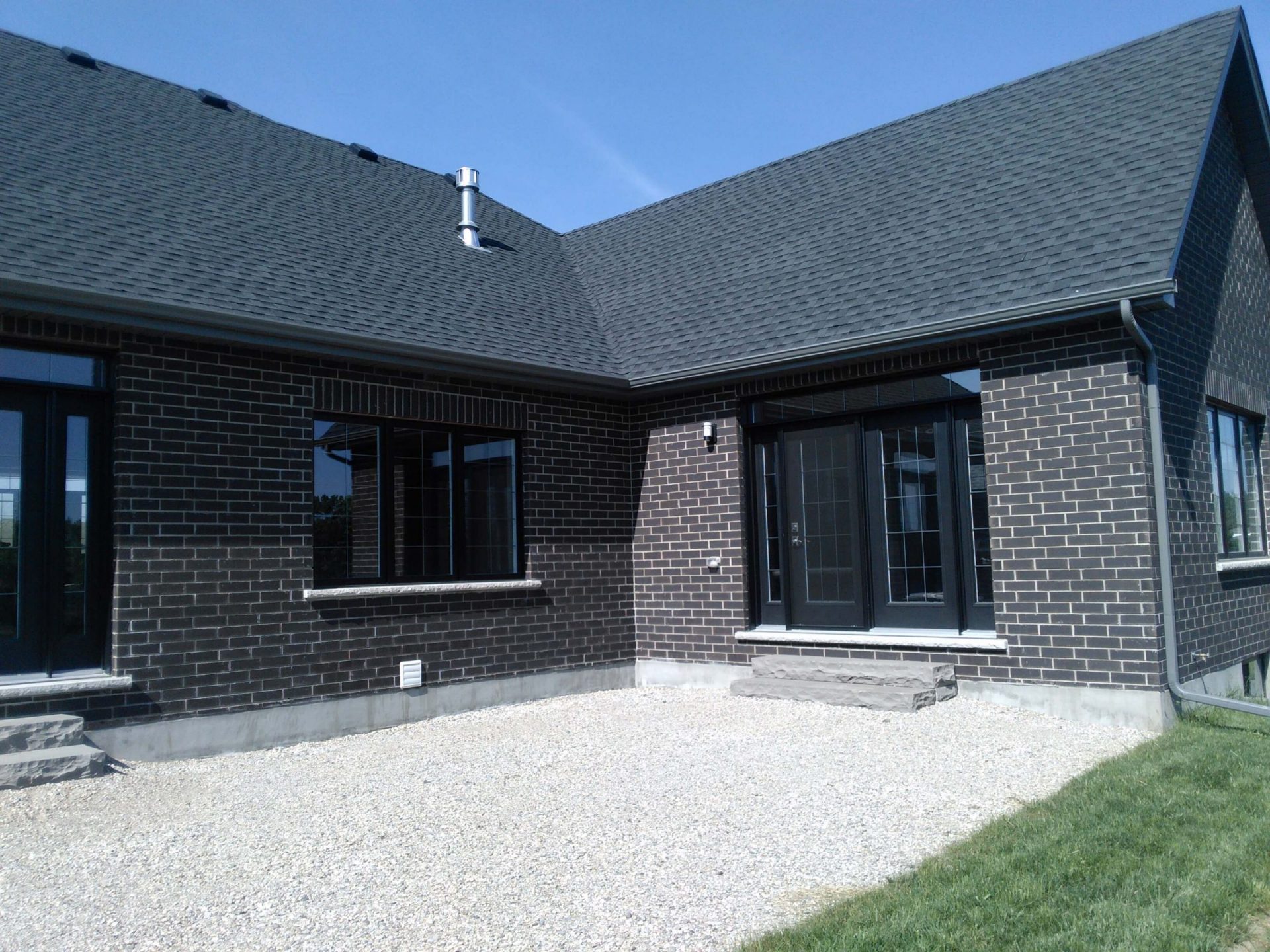 Rear patio door area with a simple gravel pad and unfinished backyard before the deck, pond, and planting installation