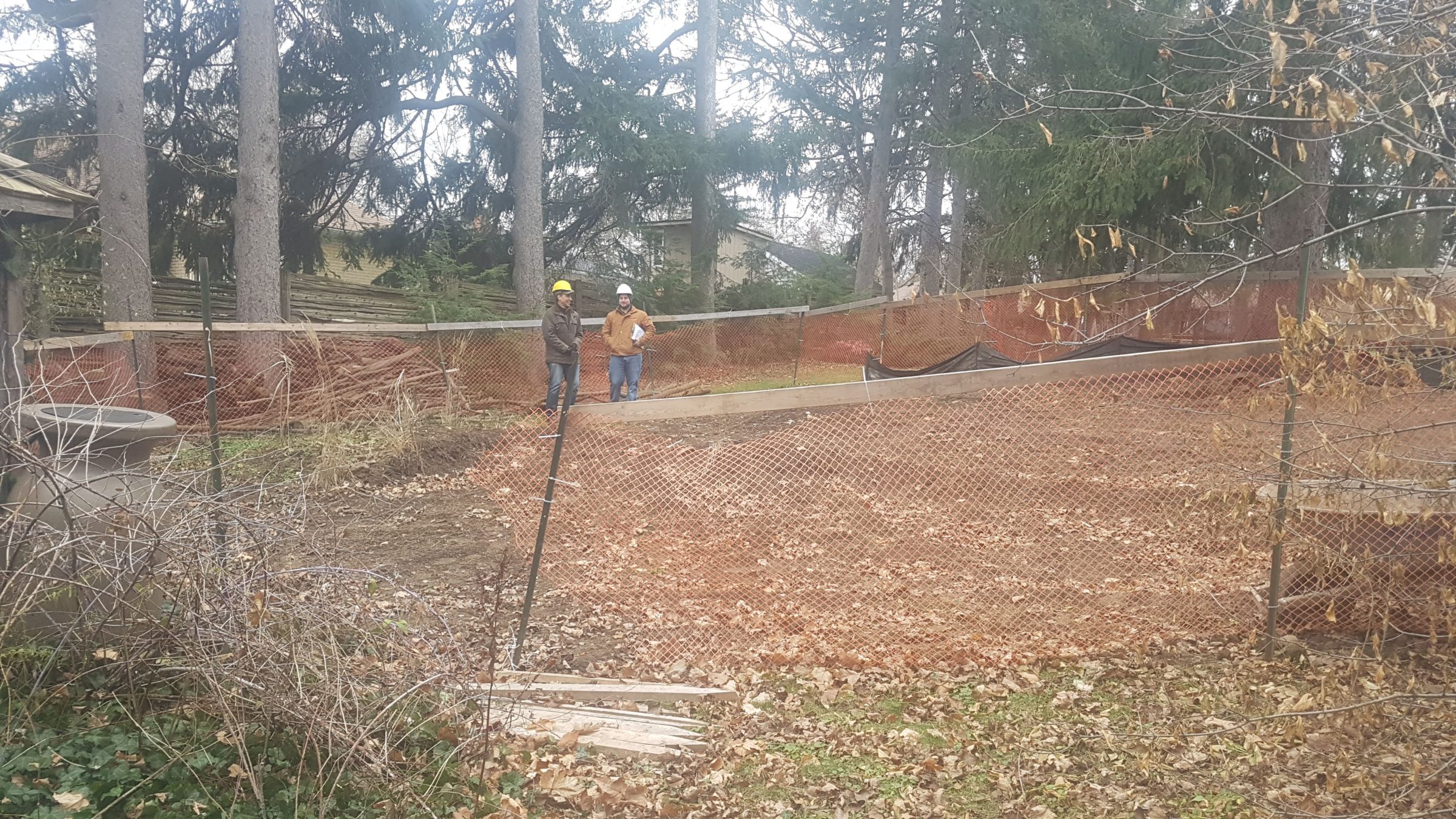 Backyard at The Junction in Guelph during early site clearing, with orange safety fencing and rough grading before the landscape build began.